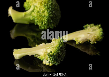 Groupe d'un ensemble de deux moitiés de brocoli vert frais isolé sur verre noir Banque D'Images