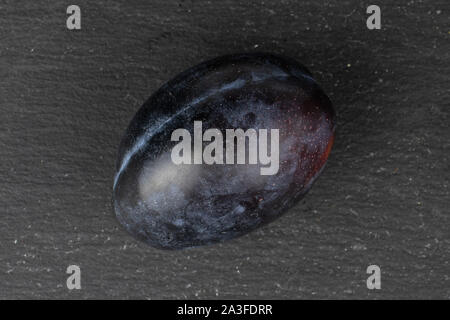 Un flatlay prune violet frais entier sur la pierre grise Banque D'Images