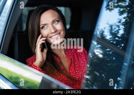 Portrait d'une business woman talking on mobile phone dans le siège arrière de la voiture. Banque D'Images