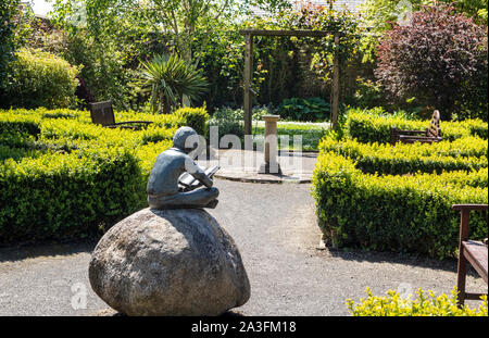 La paix et la tranquillité, d'une statue commémorative de Boy Reading in The Secret Memorial Garden, Great Torrington, Devon, UK. Banque D'Images