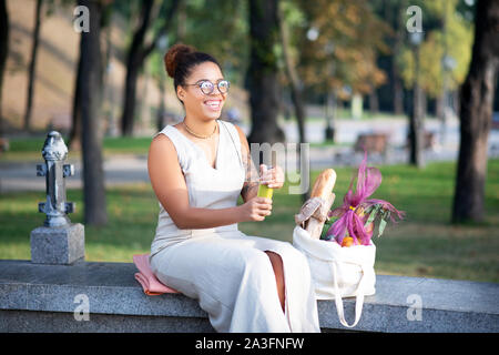 Cheerful woman drinking smoothie après avoir fait l'épicerie Banque D'Images