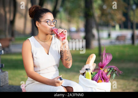 Femme boire du jus après avoir fait de courses Banque D'Images