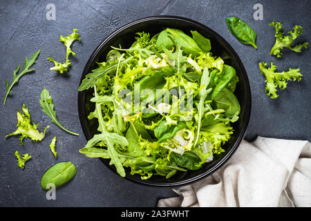 Mélanger les feuilles de salade verte sur noir vue d'en haut. Banque D'Images