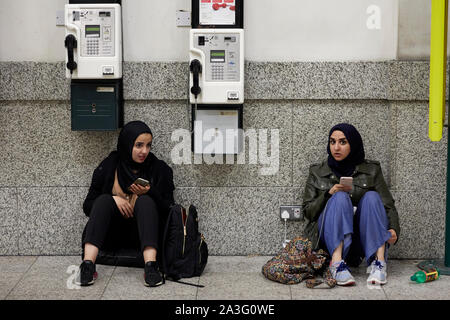 Les filles du son à l'aide d'une prise électrique pour recharger leurs téléphones portables avant de voyager à Central Station Banque D'Images