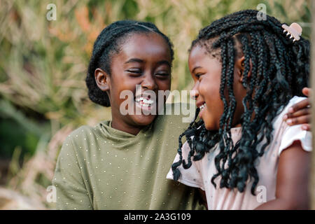 Beau rire black sisters embracing outdoors Banque D'Images