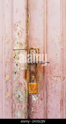 Gros plan sur l'ancien en bois, rose pâle, porte avec poignée de porte rouillée patché Banque D'Images