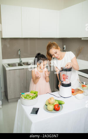 Young Asian mother and daughter making smoothies tomates fraîchement pressé, la fille est très heureux Banque D'Images