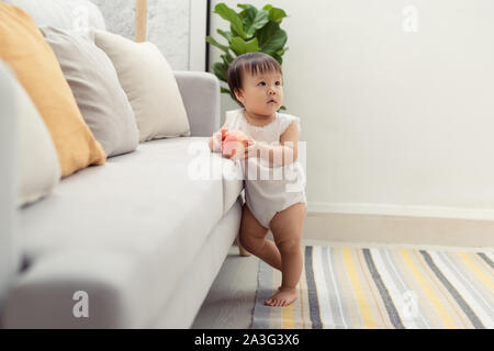 Joli bébé debout à côté du canapé. Portrait de cute baby girl happy face Banque D'Images