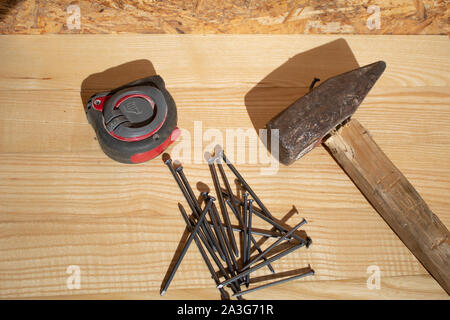 Des clous et marteau ruban de mesure sur table en bois Banque D'Images