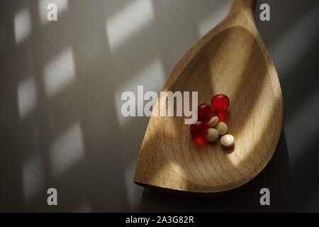 Pilules médical jaune et rouge des vitamines d'une cuillère de bois, vue du dessus sur la table with copy space Banque D'Images