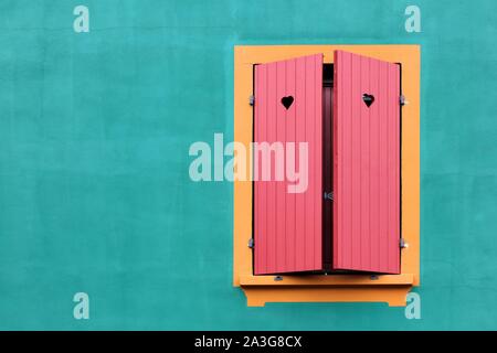 Fenêtre avec volets rouges et des petits cœurs sur un mur vert Banque D'Images