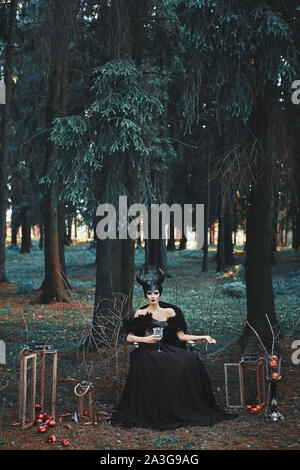 Fille modèle mystérieux avec le maquillage et les costumes pour Halloween. Modèle élégant à l'image de jeune fille posant maléfique entre mystic forest - fairytale Banque D'Images