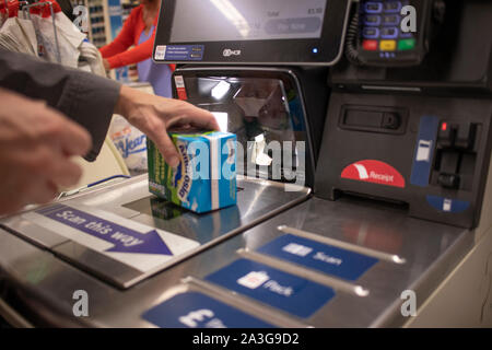 Femme de la numérisation d'un point à un self service jusqu'à un supermarché. Ces machines offrent un mécanisme permettant aux clients de traiter leurs propres achats Banque D'Images