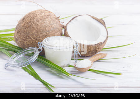 L'huile de noix de coco dans un bocal en verre hermétique et cuillère en bois blanc sur les plaques tableau Banque D'Images