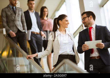Les jeunes partenaires d'affaires d'analyser les résultats de l'entreprise tout en descendant les escaliers dans un bureau moderne Banque D'Images