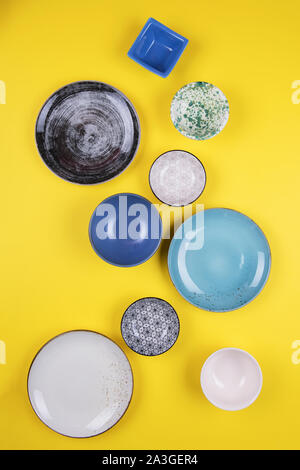 Ensemble d'assiettes en porcelaine moderne coloré et bols sur un fond jaune. designer céramique dans différentes couleurs : bleu, turquoise, gris et bleu foncé. Banque D'Images