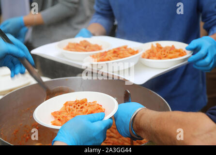 Les pâtes italiennes à la sauce tomate et les femmes avec des gants bleu Banque D'Images