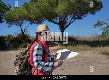 Traveler fille avec un sac à dos et une carte sur la nature du terrain, inspecte l'. Banque D'Images