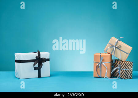 Différentes tailles, coloré, rayé et le papier ordinaire les coffrets cadeaux attachés à un ruban et s'incline sur une surface bleue et l'arrière-plan. Close-up, copiez l'espace. Banque D'Images