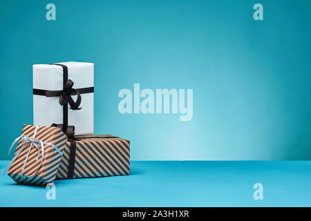 Différentes tailles, coloré, rayé et le papier ordinaire les coffrets cadeaux attachés à un ruban et s'incline sur une surface bleue et l'arrière-plan. Close-up, copiez l'espace. Banque D'Images