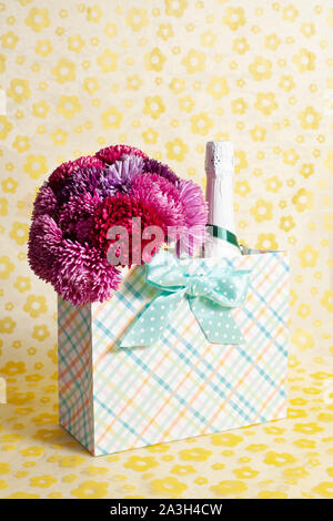 Un bouquet d'Aster chinensis Callislephus dans un sac-cadeau sur fond jaune Banque D'Images