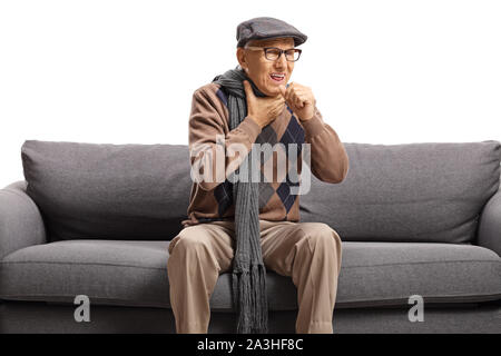 Un homme âgé assis sur un canapé et la toux isolé sur fond blanc Banque D'Images
