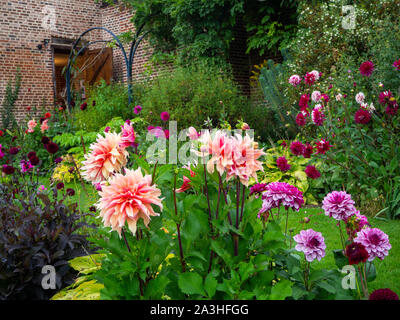 Chenies Manor sunken garden dahlia afficher sur une soirée septembre.Un chemin mène à la pavillon restauré. Un feu est allumé dans la vieille porte. Banque D'Images