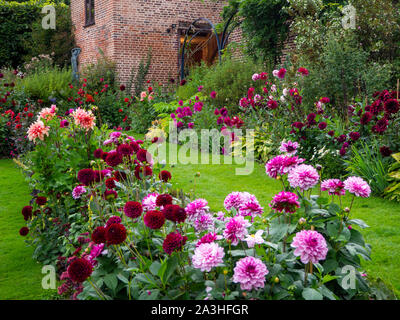 Chenies Manor sunken garden dahlia afficher sur une soirée septembre.Un chemin mène à la pavillon restauré. Un feu est allumé dans la vieille porte. Banque D'Images