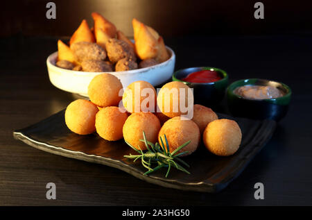 Snack-brésilien bolinha de queijo, boules frites farcies de fromage sur fond sombre. Focus sélectif. Banque D'Images