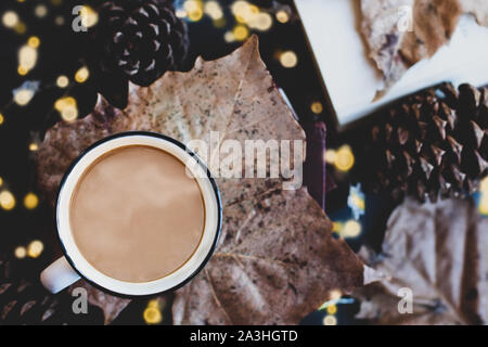 Sex, tasse fumante de café séché sur une feuille d'automne au sommet d'une pile de livres. Entouré par les cônes de pins, de feuilles et de livre ouvert avec une mise au point sélective extre Banque D'Images