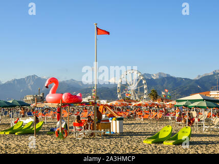 Vue panoramique sur la plage de sable de Lido di Camaiore avec un gonflable rose flamingo, chaises longues de plage moderne et une roue panoramique, Toscane, Italie Banque D'Images