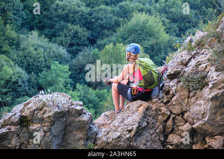 Femme assise sur des rochers et à admirer la vue à partir de la Casa Zmeului via ferrata itinéraire dans Padurea Craiului, Roumanie, aux côtés de la rivière Crisul Repede Banque D'Images