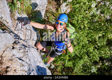 Happy smiling tourist montrant un signe de victoire en grimpant en haut d'une via ferrata vélo à Vadu Crisului, Roumanie, sur une paroi rocheuse appelée Peretele Zane Banque D'Images