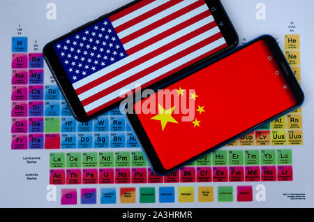 La photo d'USA et de la Chine les drapeaux sur les smartphones Huawei qui jettent sur la table périodique d'un groupe de minéraux de terres rares. Conceptuel. Banque D'Images