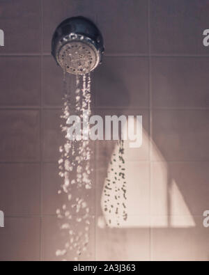 Cours d'eau de douche tête comme lumière du matin rend les formes sur mur Banque D'Images