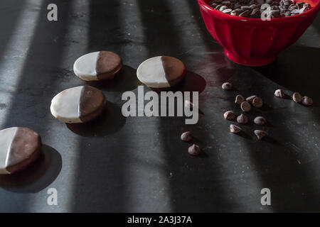 Les cookies en noir et blanc et rouge bol de chocolat sur le tableau noir Banque D'Images