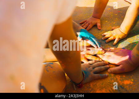 Les mains des enfants remplis de poudres colorées sur le sol rouge Banque D'Images