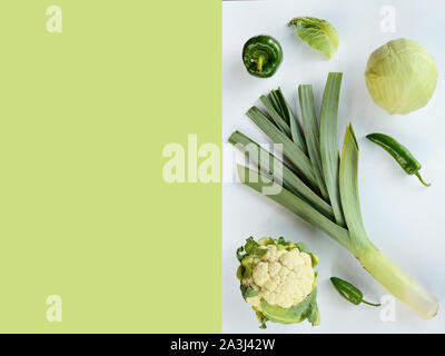 Mise en page créative faite de courgette poireau vert chou-fleur et de piment . Mise à plat. Concept alimentaire. Les légumes vert isolé sur fond vert-blanc Banque D'Images