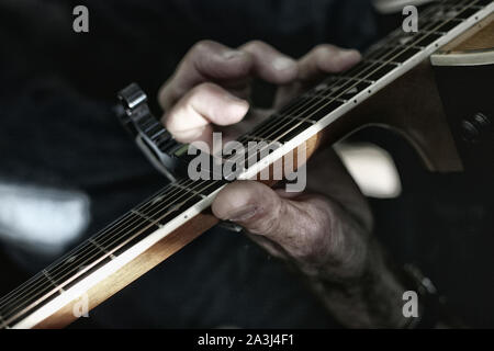 Close up of old main jouant une guitare acoustique Banque D'Images