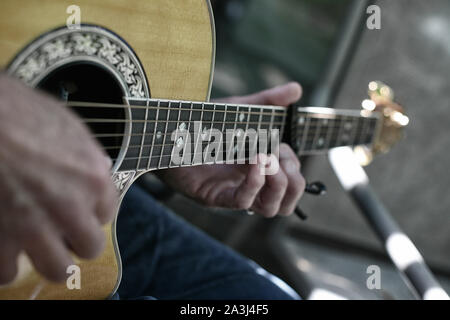 Gros plan d'une paire de mains de gratter une guitare Banque D'Images