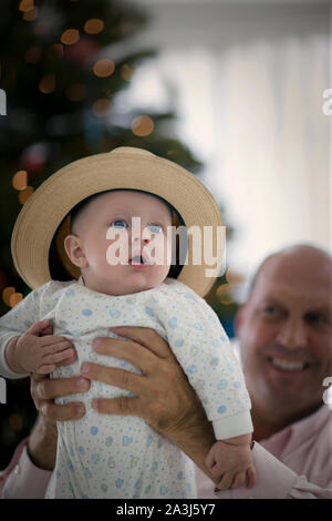 Portrait d'un jeune bébé portant un chapeau alors qu'eu lieu en altitude par son père sourire. Banque D'Images