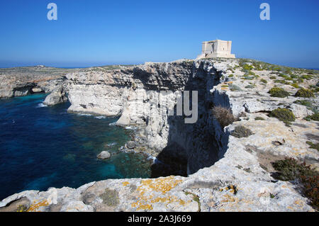 Blue Lagoon avec hautes falaises et Santa Marija Tower sur rumeurs Round Up Island à Malte (Torri ta' Kemmuna) Banque D'Images