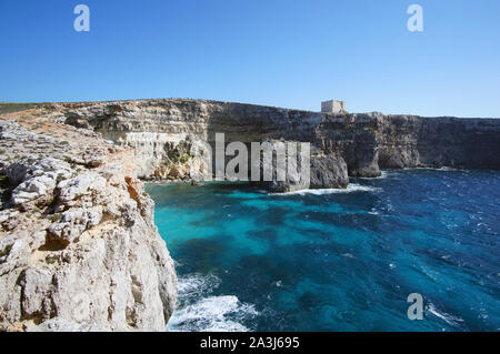 Blue Lagoon avec hautes falaises et Santa Marija Tower sur rumeurs Round Up Island à Malte (Torri ta' Kemmuna) Banque D'Images