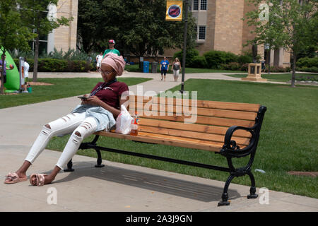 Femme musulmane étudiant avec téléphone cellulaire portant un hijab ou casque assise sur un banc à l'Université St.Thomas. St Paul Minnesota MN USA Banque D'Images