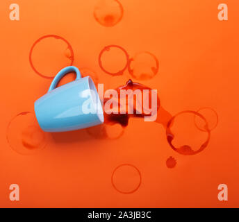 Renversé du café sur une table avec des gouttes et liquide, clair sur fond orange Banque D'Images