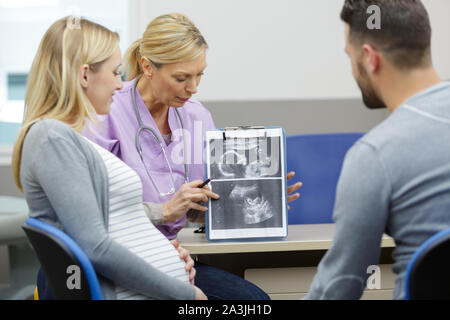 Médecin montrant le couple de numérisation d'images bébé à venir Banque D'Images