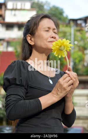 Une femme Portrait Senior Smelling Flowers Banque D'Images