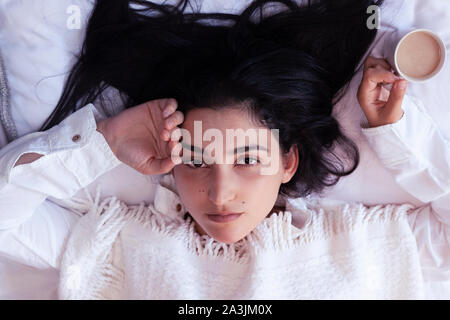 Beauty woman drinking coffee in bed après le réveil le matin. Belle jeune femme au lit avec une tasse de café. Dame mignon le réveil. Petit-déjeuner dans un c Banque D'Images