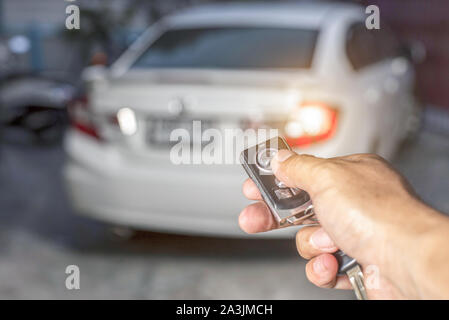 La main de l'homme appuie sur la commande à distance des systèmes d'alarme de voiture Banque D'Images