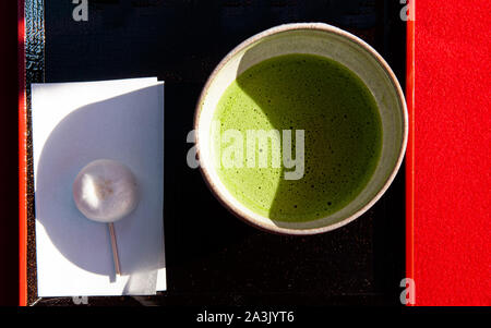 Thé vert japonais Matcha dans un bol en céramique sur plateau noir et rouge vue d'en haut droit Banque D'Images
